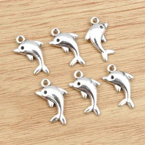 Set of six silver alloy dolphin charms for DIY jewelry making on wooden background