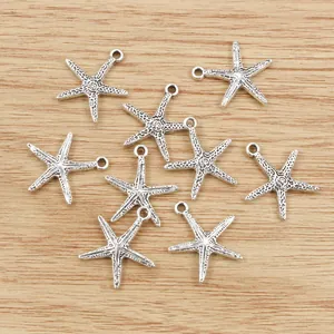 Set of antique silver starfish charms with loops on textured wooden background
