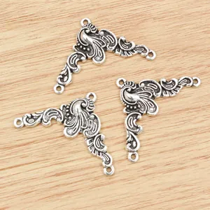 Three antique silver flower alloy connectors for DIY jewelry making on wood background