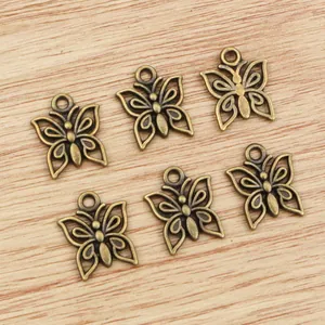 Antique bronze butterfly pendants for jewelry making displayed on a wooden surface