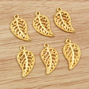 Detailed view of six hollow leaf pendants in gold finish on a natural wood surface