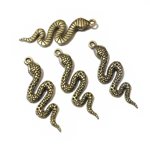 Macro view of four vintage bronze snake pendants with detailed scales for DIY jewelry making