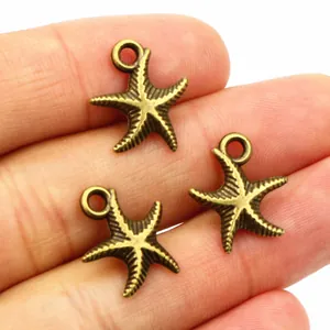 Detailed view of three bronze starfish alloy charms held in hand to show size