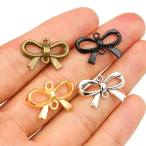DIY metal bow charms in four colors held on fingers to show the 22x15mm scale