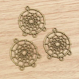 Three bronze alloy dreamcatcher charms for DIY jewelry making on wood background