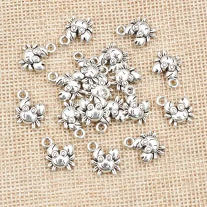 Bulk silver crab alloy charms for DIY jewelry making on natural burlap background