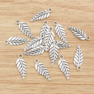 Silver alloy feather pendants for DIY jewelry making on a light wood background