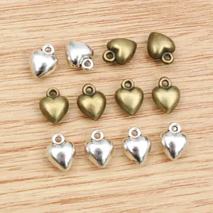 Macro shot of 3D alloy heart charms in silver and bronze finishes on wood background
