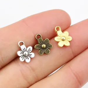 Colgantes de flores en plata bronce y oro en la punta de un dedo muestran el tamaño DIY