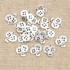 Zilveren knoopvormige bedeltjes van legering voor DIY-sieraden op jute achtergrond