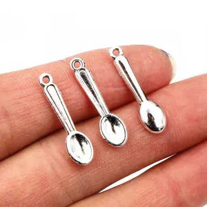 Three vintage silver spoon pendants for DIY jewelry making shown held in hand for scale