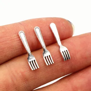 Three vintage silver alloy mini fork charms held on fingertips for jewelry DIY projects