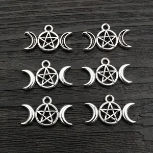 Antique silver moon and pentagram alloy charms for DIY necklaces on wood background