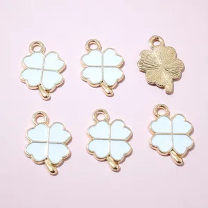 Détail de six pendentifs trèfle en émail blanc et texture dorée pour création de bijoux