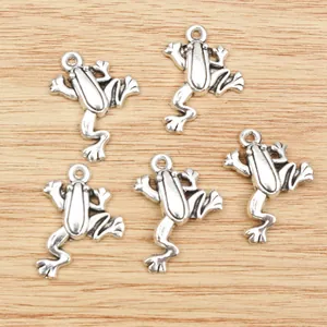 Five vintage silver alloy frog pendants for DIY jewelry making on wooden background