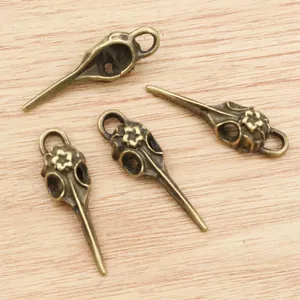 Bronze bird skull charms for jewelry making, 41x13mm vintage alloy pendants on wood surface