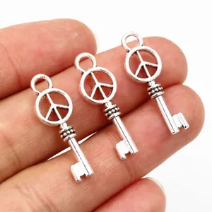 Drie vintage zilveren vredesteken sleutelhangers voor DIY sieraden in een hand