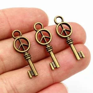 Detailopname van drie vintage bronzen vredesteken sleutelhangers op een handpalm