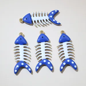 Dettaglio di quattro ciondoli a lisca di pesce in smalto blu e bianco con bordo dorato
