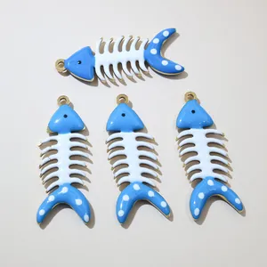 Dettaglio di quattro ciondoli a lisca di pesce dorati con smalto blu e pois bianchi