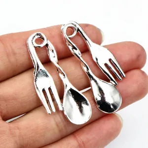 Makroaufnahme von Besteckanhängern aus Silberlegierung für DIY-Schmuck in der Hand