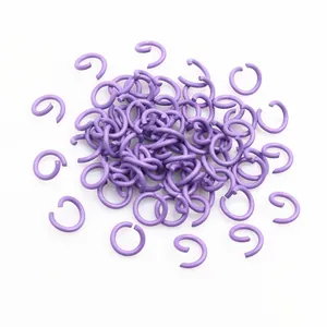 Vista macro di anellini aperti viola per creazione di gioielli fai-da-te su bianco