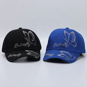 Detail view of rhinestone butterfly pattern on black and blue cotton baseball caps