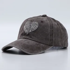 Macro detail of silver rhinestone heart embellishment on washed cotton baseball cap