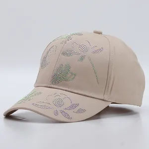 Detail of beige cotton baseball cap featuring colorful rhinestone butterfly and floral patterns
