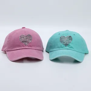 Close-up of pink and blue washed cotton baseball caps with sparkling rhinestone heart design