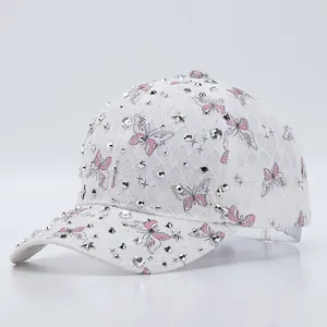 Détail de la casquette en dentelle blanche avec motif papillon rose et strass argentés