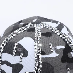Gros plan d'une casquette camouflage avec des strass argentés brillants et des franges