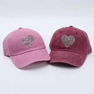 Detail of pink and wine red washed cotton baseball caps with sparkling rhinestone heart