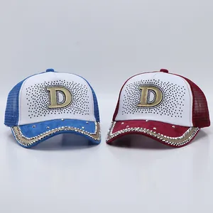 Dettaglio del cappellino con strass e grande logo in metallo dorato con la lettera D
