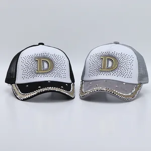 Dettaglio di cappelli trucker in mesh traspirante con visiera di strass e logo D in metallo