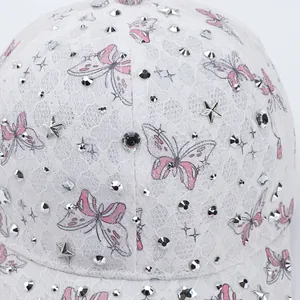 Détail d'une casquette en dentelle blanche avec papillons roses et strass argentés brillants