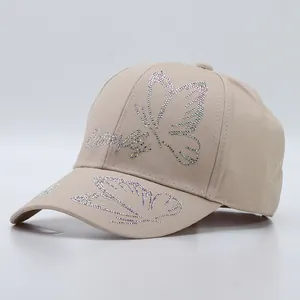 Detail of rhinestone butterfly and text embellishments on beige cotton baseball cap