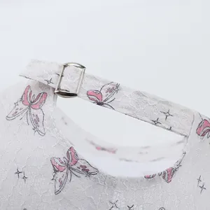 Détail de casquette blanche en dentelle avec papillons roses et boucle en métal