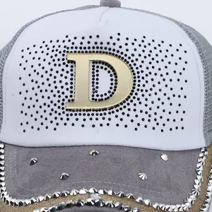 Dettaglio macro della lettera D con strass su pannello bianco e berretto da baseball in mesh