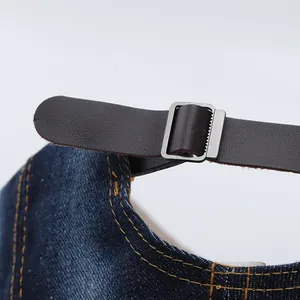 Macro shot of adjustable brown leather strap and metal buckle on denim baseball cap