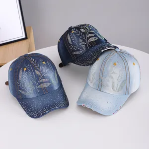Detailed view of three denim baseball caps with rhinestone leaf patterns and worn brims