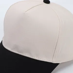 Detail of two-tone cotton baseball cap showing beige crown and black visor stitching