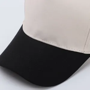 Close-up of beige cotton baseball cap with black brim and detailed twill stitching