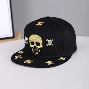Close-up of golden skull and crossbones studs on a black flat brim hip-hop cap