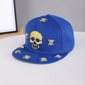 Detail of blue flat brim hip-hop hat with gold skull studs and metallic rivets