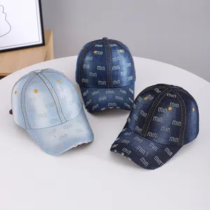 Three denim baseball hats with rhinestone letters and yellow dot patterns on a white table