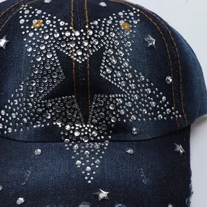 Detail of dark blue denim baseball cap featuring crystal star and metal rivet studs