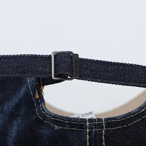 Close-up of denim baseball cap back with adjustable strap and metal buckle