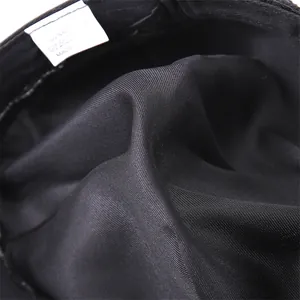 Detailed macro view of 100% cotton fabric texture and wash label on the black docker hat