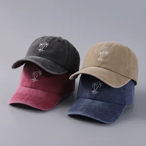 Detailed stack of washed cotton baseball caps with embroidered coconut tree patterns